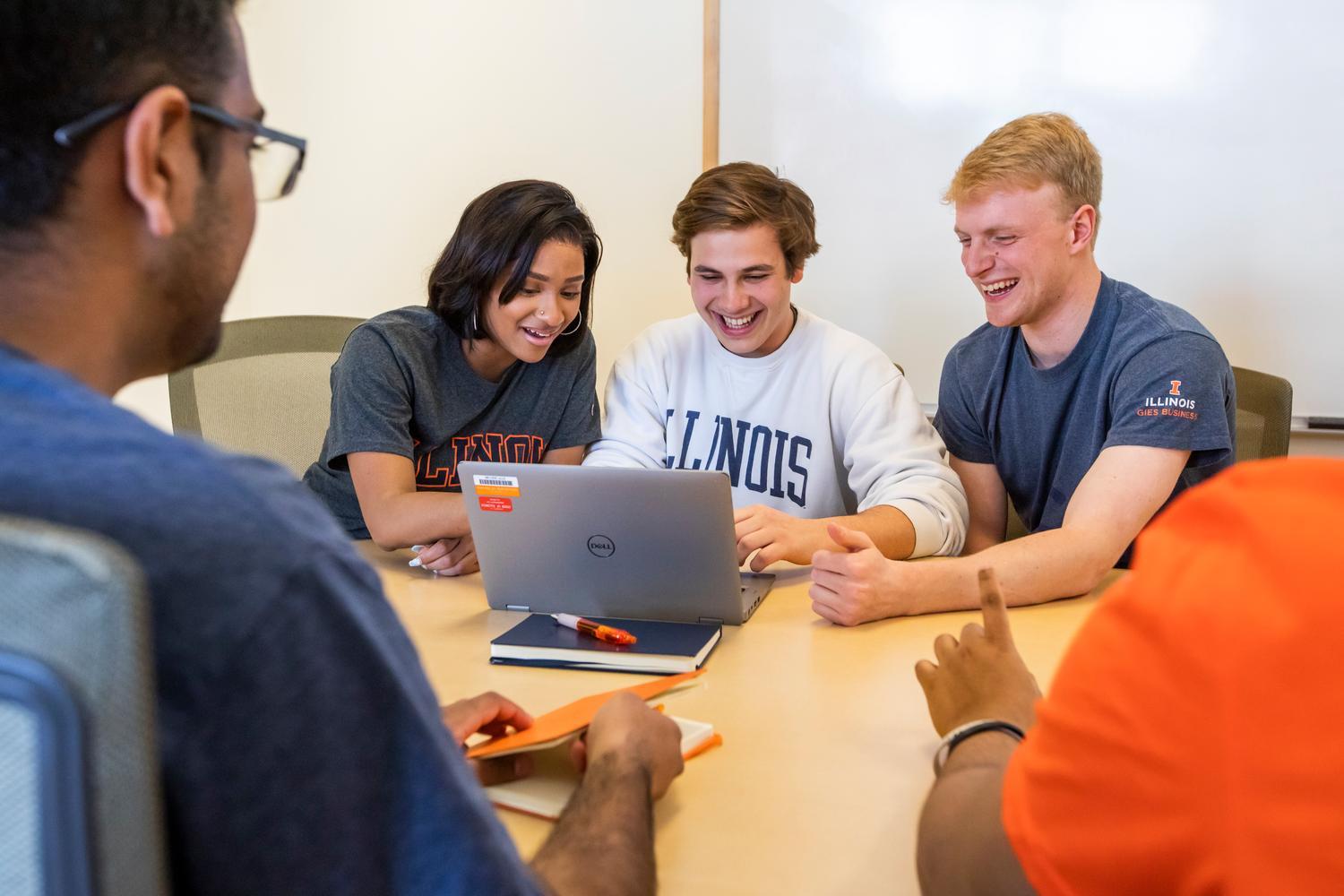 Students sitting at table look at laptop