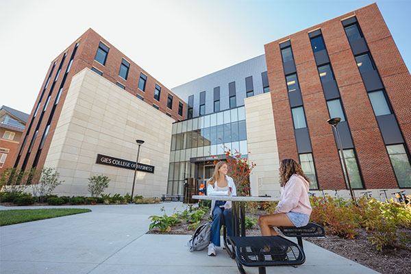Two students talking at table outside of Wymer Hall