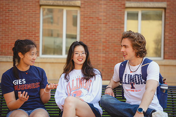 Three Gies Undergraduate Students Sitting on Bench Outside Business Instructional Facility
