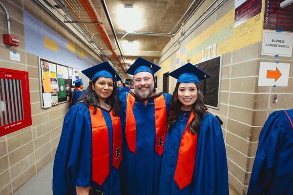 Three online learners in caps and gowns at graduation ceremony