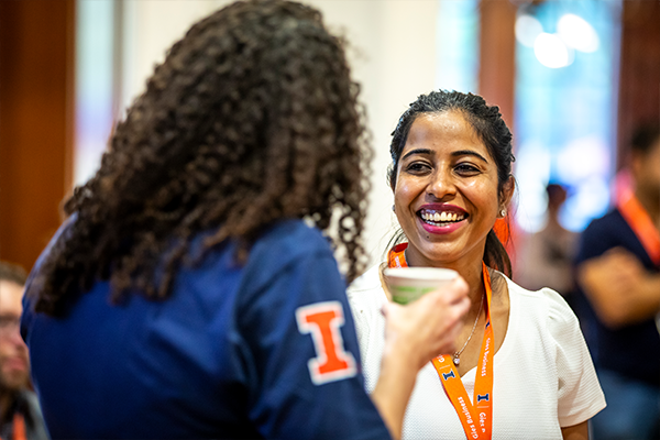 Two women talking and smiling while holding coffee