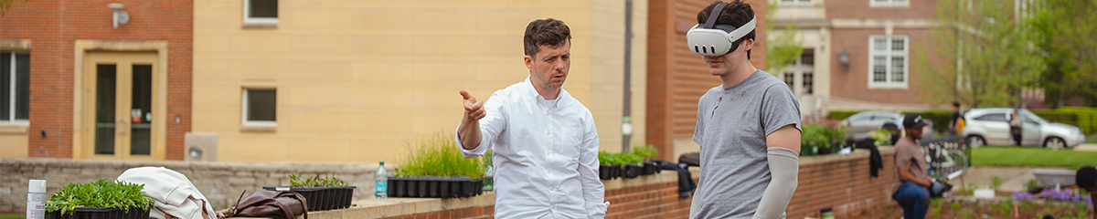 Faculty and student discussing planting outside Wymer Hall